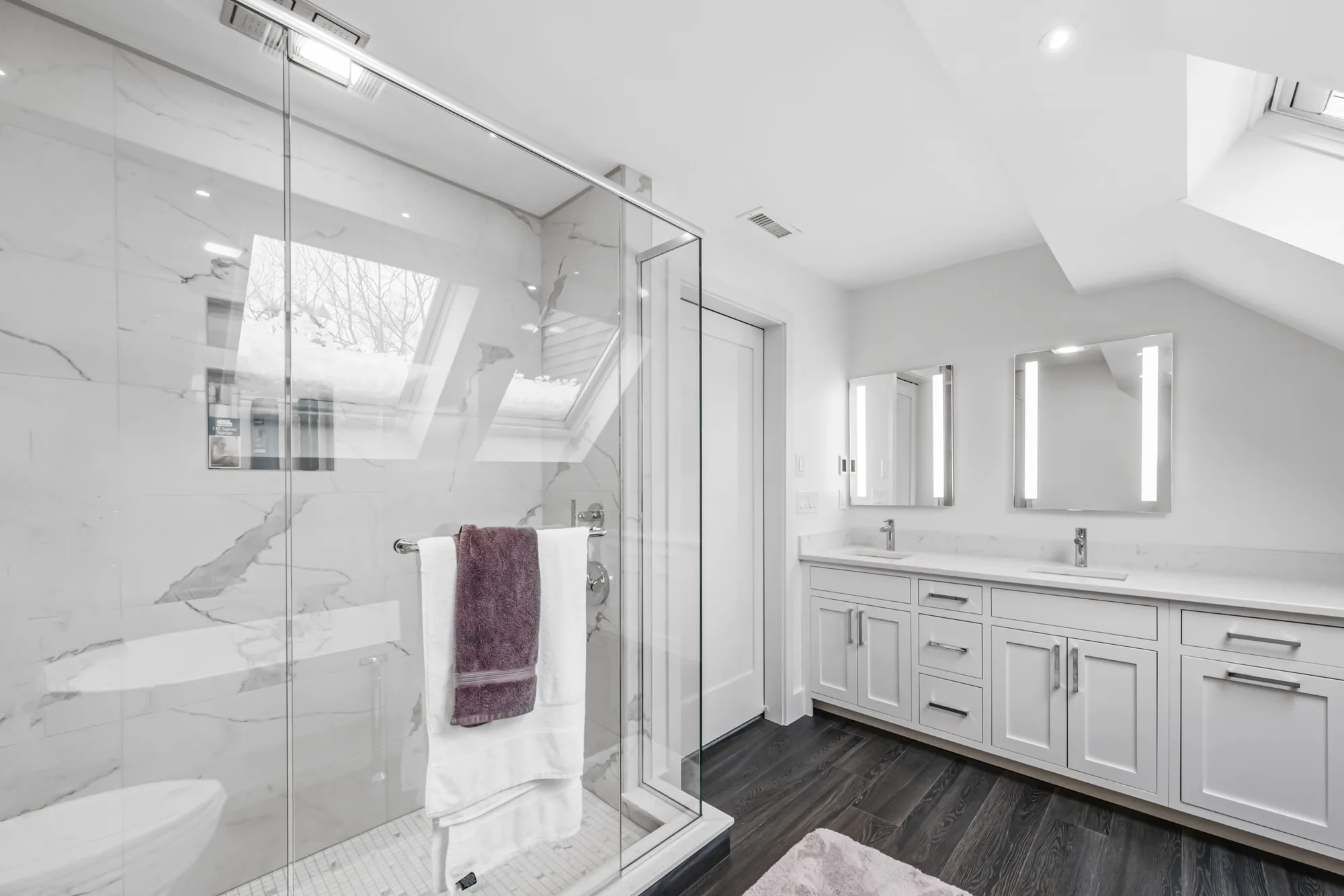 Bathroom with a glass-enclosed marble shower and a white double vanity