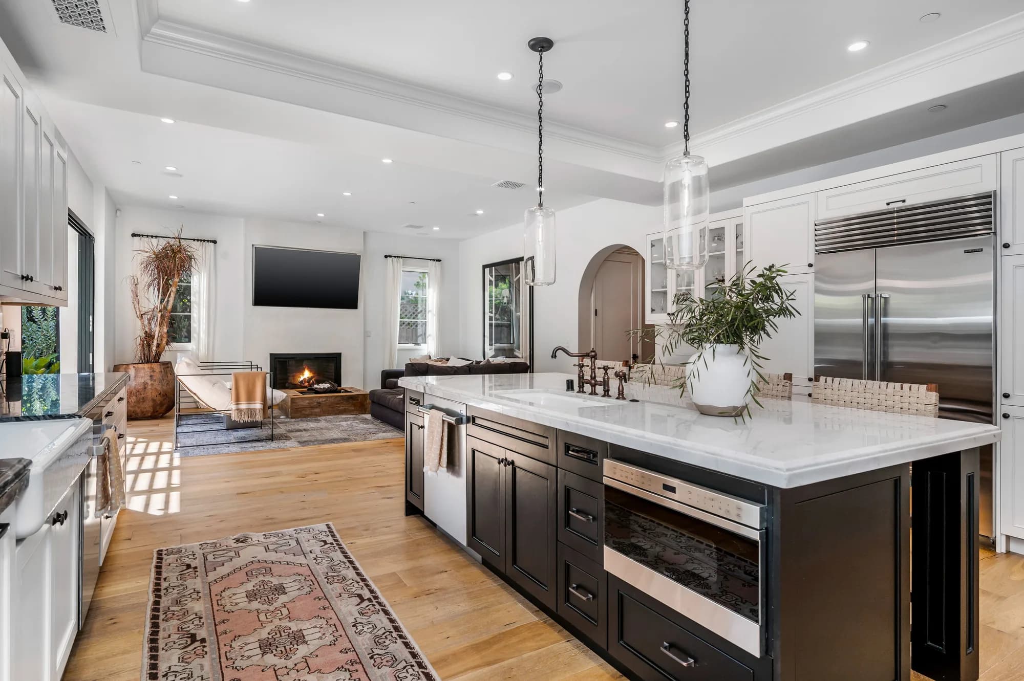 Kitchen with a marble-topped dark island, white cabinetry, and glass pendant lights