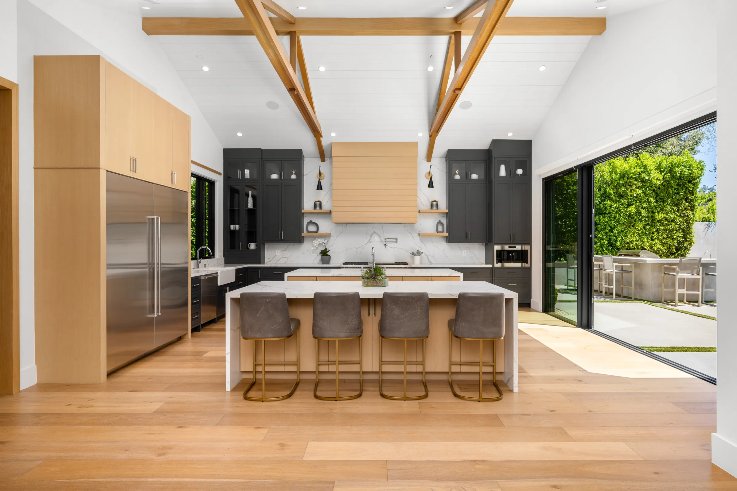 Kitchen with timber ceiling beams, oak and charcoal cabinetry, and an island with four stools